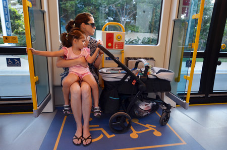 GOLD COAST, AUS - NOV 04 2014:Mother travelling with a pram sit on accessibility seat in a tram.The space is secured for disabled people, older people and pram users.のeditorial素材