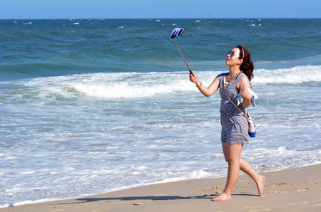 SURFERS PARADISE, AUS - NOV 01 2014:Asian woman take selfie photo on the beach. Over 1 Million selfies Are taken each day.Instagram has over 53 million photos tagged with the hash tag #selfie.のeditorial素材