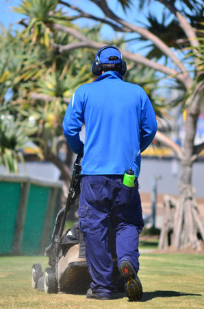 GOLD COAST, AUS - OCT 16 2014:Worker cutting grass during lawn cutting service.85 million households in the US have private lawnsのeditorial素材
