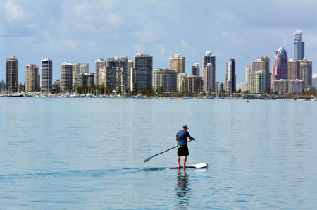 GOLD COAST - SEP 27 2014:Man on stand up paddling in Surfers Paradise. It's one of Australia's iconic coastal tourist destinations, drawing 10 million tourists every year from all over the world.のeditorial素材