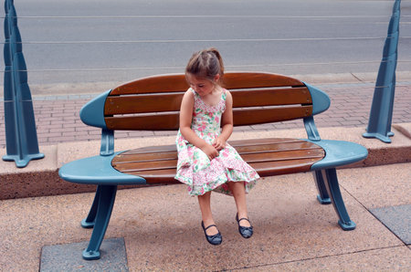 SURFERS PARADISE - NOV 18 2014:Little girl Talya Ben-Ari age 04 sit on a bench in a shape of a surfing board in Surfers Paradise, one of Australia's iconic coastal tourist destination.のeditorial素材