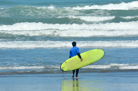MURIWAI, NZL -  JAN 01 2015:A man surf in Muriwai beach.It's a very popular beach in New Zealand known for it beauty and for its outdoor activities such as swimming, surfing, biking and fishing.のeditorial素材