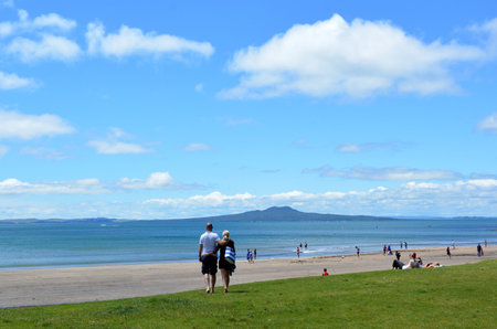 AUCKLAND, NZL - DEC 21 2014:Visitors on a beach overlooking Rangitoto Island.The 5.5 km wide island is an iconic landmark of Auckland with distinctive symmetrical volcano cone rising 260 m 850 ft highのeditorial素材