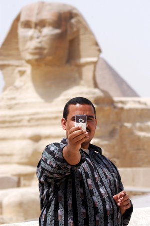 CAIRO - APRIL 27: Egyptian tman takes photos with his mobile phone of himself with the Sphinx on April 27 2007 in Cairo, Egypt.There is 90 million cell phone subscriptions in Egypt alone.のeditorial素材