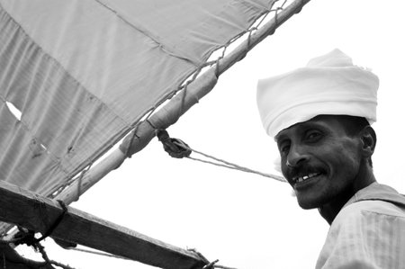 ASWAN - APRIL 30:An Egyptian Nubian man sail a boat on the Nile near Aswan, Egypt on April 30 2007.It's ethnic group originally from northern Sudan, and southern Egypt.のeditorial素材