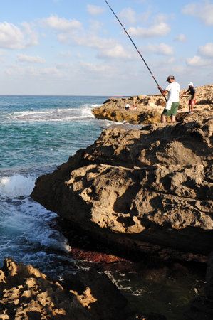 ZICHRON YAAKOV, ISR - AUG 07: Reef fishermen are fishing at sanctuary Dor Habonim beach on Au 07 2009. It's one of the top 10 most beautiful beaches in Israel!.のeditorial素材