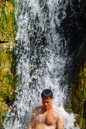 EIN GEDI, ISR - MAR 18 :Man bath in waterfall in Ein Gedi spring on March 18 2009. It's a very famous and popular  oasis on the shore of Israel's Dead Sea, the lowest place on Earth.のeditorial素材