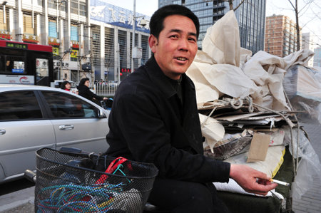 BEIJING - MARCH 15:Chinese man smoke cigarette in the street on March 15 2009 in Beijing, China. Chinese consume 3 million cigarettes every minuteのeditorial素材