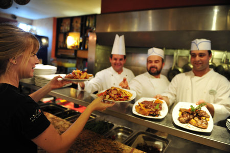 ASHKELON - JULY 27: Chefs passing delicious food to a woman waitress in a restaurant on July 27 2009, in Ashkelon, Israel.のeditorial素材