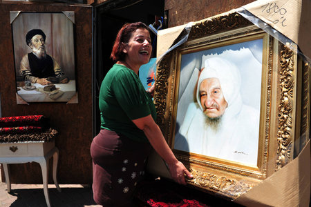 NETIVOT, ISR - AUG 24:Jewish woman holds oil paintings of "Baba Sali" on Aug 24 2009.Rabbi Yisrael Abuhatzeira was kabbalist who renowned for his alleged ability to work miracles through his prayers.のeditorial素材