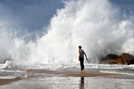 ASHKELON - NOV 02:Israeli man walk into a giant wave on Nov 02 2009.According to a recent research about consequences of rising sea levels, a six-meter tsunami waves can strikes Israel's coast.のeditorial素材