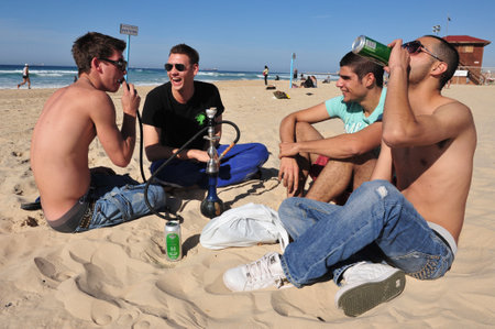 ASHDOD, ISR - JAN 16:Young Israeli men smoke and drink alcohol on January 16 2010.The Israeli law prohibits selling or serving alcohol to minors, however the law does not prohibit minors to drink.のeditorial素材