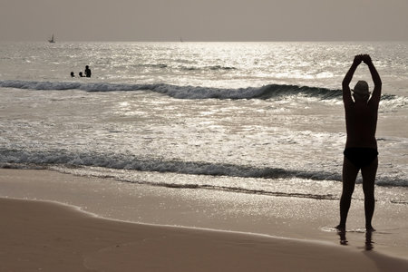 Silhouette of a man enjoying summer at sunset on a beach by exercisingのeditorial素材