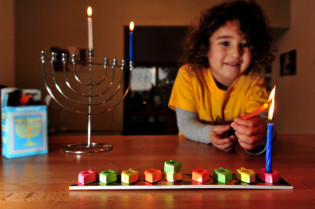 Jewish girl is lighting the first candle for the Jewish holiday of Hanukkah. Hanukkah or Chanukah, Chanukkah, or Chanuka, also known as the Festival of Lights, is an eight-day Jewish holiday. Hanukkah is observed for eight nights and days.のeditorial素材