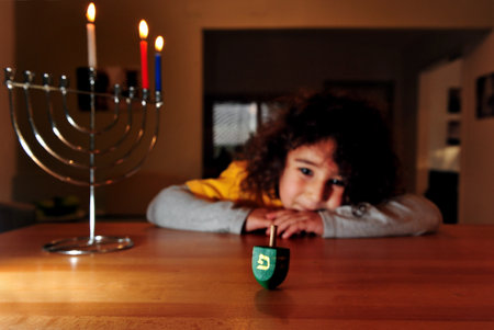 Jewish girl plays with dreidel during the Jewish holiday of Hanukkah. Hanukkah or Chanukah, Chanukkah, or Chanuka, also known as the Festival of Lights, is an eight-day Jewish holiday. Hanukkah is observed for eight nights and days.のeditorial素材