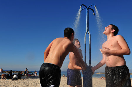 ASHDOD - JAN 09:Young Israeli man cools down under beach water shower on Jan 09 2010.The highest recorded temperatures in Israel was 129 Fahrenheit Degrees (54 Celsius) in Tirat Tsvi on June 21 1942.のeditorial素材