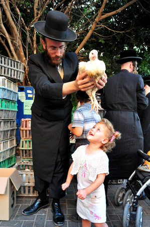 ASHDOD - SEPTEMBER 15 : Ultra orthodox Jewish man waves a chicken over his daughter head during the "Kaparot" ceremony held on September 15 2010 in Ashdod Israel.のeditorial素材