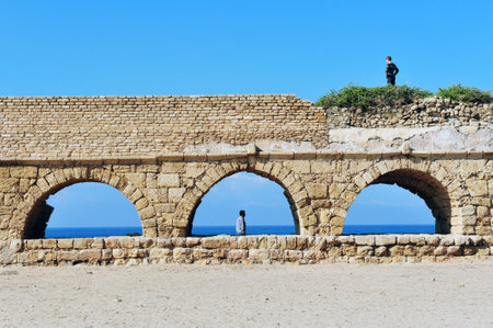 CAESAREA - DEC 13:Visitors at the ancient Roman aqueduct at Ceasarea on Dec 13 2009. The ancient Caesarea Maritima city and harbor was built by Herod the Great about 2513 BCE.のeditorial素材