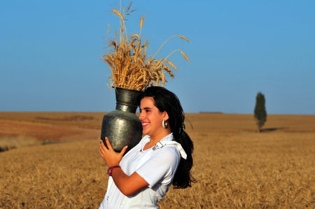 KIRYAT GAT - MAY 24: Israeli girl in a wheat field celebrate the Jewish holiday Shavuot by carry the first wheat harvest in a pitcher on May 24 2009 near Kyryat Gat, Israel.It's Judaism's third largest feast which commemorates the handing down of the fiveのeditorial素材