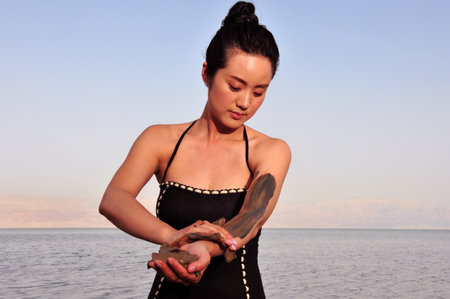 DEAD SEA, ISR - MAY 14:Young Chines woman is enjoys natural mineral mud on May 14 2010.The Dead Sea is filled with minerals including calcium, iodine, saline, potassium, and bromide.のeditorial素材
