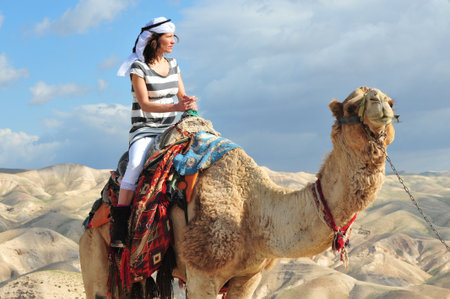 JERICHO - MAR 18:Woman tourist during camel ride on March 18 2010 in the Judean Desert, Israel.It's a rain shadow desert located between Jerusalem to Jericho 85 miles long and 25 miles wide.のeditorial素材