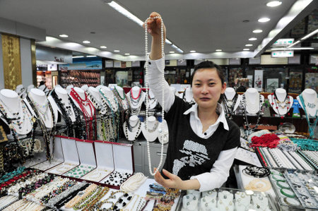 BEIJING -MARCH 14:Chinese woman sales pearl necklace at Beijing Pearl market on Mar 14 2009 in Beijing, China.It's a famous mega-market that attracts many tourists looking for China's well known pearls.のeditorial素材