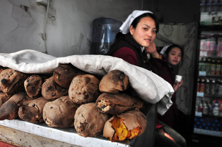 BEIJING - MARCH 11:Chinese women sells hot sweet potatoes on March 11 2009 in Beijing, China.Millions of Chinese people eat street food every day.のeditorial素材