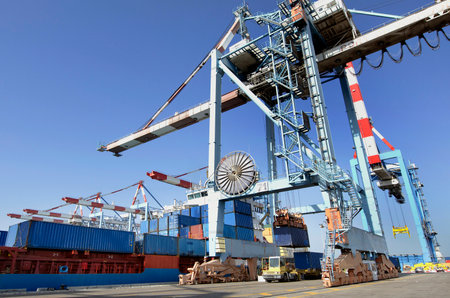 A big container vessel in a container seaport during transportation of cargo in containers by cranes...
