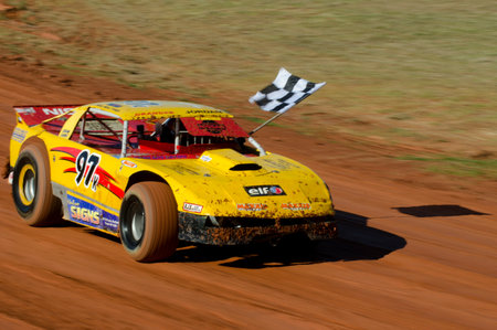 TAIPA, NEW ZEALAND - JUNE 02 2012:A winner of a super stock cars category carry a checkered flag during a dirt track racing on June 02 2012 in Taipa speedway, New Zealand.のeditorial素材