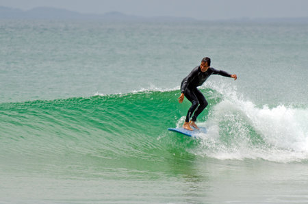 HENDERSON BAY - JAN 20: An old man wave surfing in Henderson Bay on January 20 2013.It's a beach...