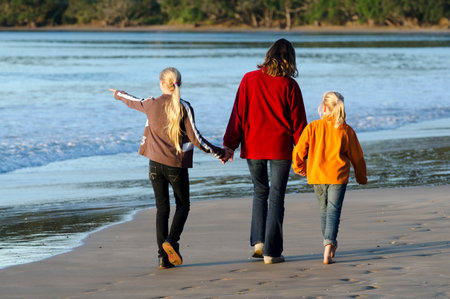 Mother and here two daughters walks on the beach.のeditorial素材
