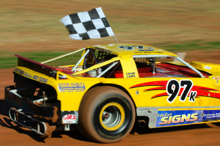 TAIPA, NEW ZEALAND - JUNE 02 2012:A winner of a super stock cars category carry a checkered flag during a dirt track racing on June 02 2012 in Taipa speedway, New Zealand.のeditorial素材