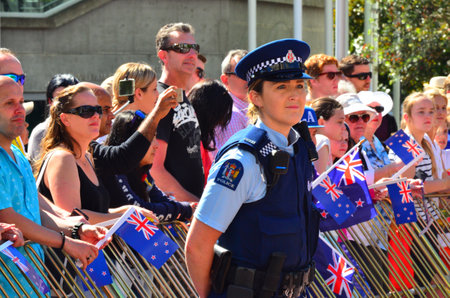 AUCKLAND,  NZL - AUG 01 2015:New Zealand police officer woman guarding crowd of people.With over...