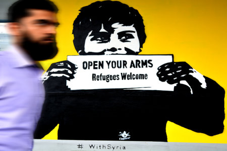 AUCKLAND - NOV 20 2015:Middle eastern man pass by Graffiti reads: "Refugees Welcome".Each year New Zealand accepts 750 refugees as agreement with the United Nations High Commissioner for Refugees.のeditorial素材