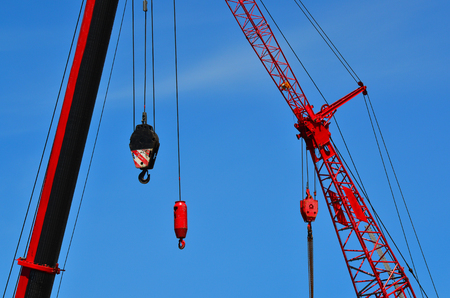 Red cranes in construction site against blue sky. Construction work conceptの写真素材
