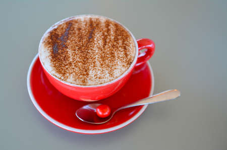Cappuccino art coffee served in a red mug on clear bright table background with copy spaceの写真素材