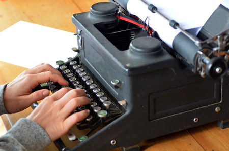 Hand of a young woman writer writing on antique typewriter.Side view - Type Writing Conceptの写真素材