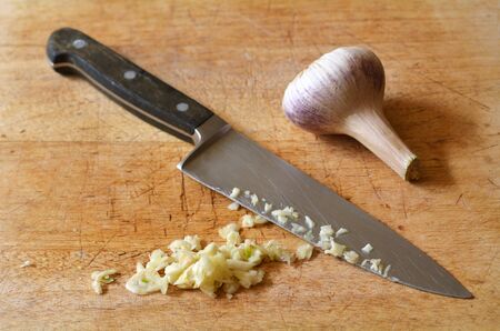 Chopped garlic on a wooden board, with kitchen knife.の写真素材