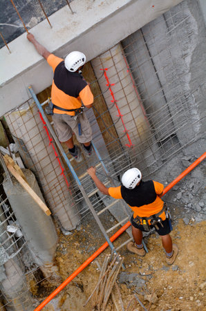 Aerial view of two unrecognised  manual workers inspecting a concert wall in construction site.Building development concept with copy spaceのeditorial素材