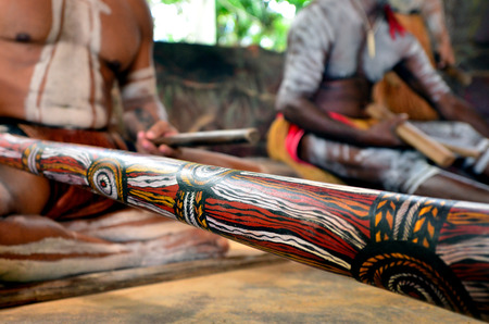 Yirrganydji Aboriginal men play Aboriginal music on didgeridoo and wooden instrument during Aboriginal culture show in Queensland, Australia.の写真素材