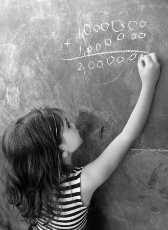 Smart child (girl age 5-6) calculat and solve hard mathematic equation on a cluck board in school. Education cocept with copy space textの写真素材