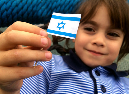 Israeli child (girl age 5-6) holds small Israel flag during Israel's independents day.の写真素材