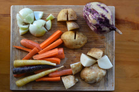 Flat lay of raw root vegetables on a wooden cutting board .Food background and texture with copy...