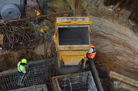Aerial to view of concreting work: construction site worker during concrete pouring into formwork at...