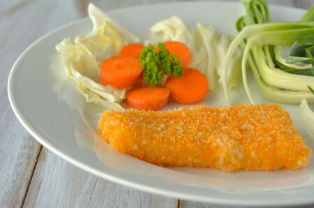 Crumbed fish fillet served on a plate with vegetables. Pescetarian diet concept. Food background and...