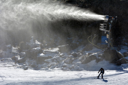 NATIONAL PARK, NZL - JULY 12 2016:Snow Gun Snowmaker throw snow over a snowboarder in Whakapapa skifield on Mount Ruapehu in Tongariro National Park in the North Island of New Zealand on winter seasonのeditorial素材