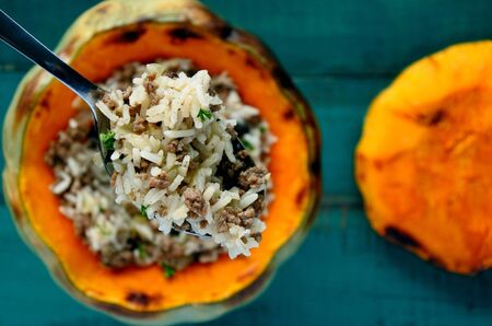 Close up details of a spoon with rice and mince over a stuffed pumpkin. Food background. copy spaceの写真素材