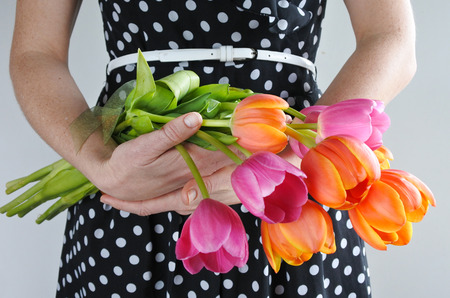 Center body view of a woman in a dress holds Tulip flowers bouquet. Women holidays concept.  copy spaceの写真素材