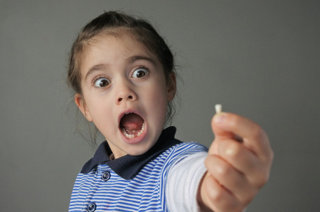 Young girl (age 6) surprise to find that she have lost her first bottom front milk teeth. Childhood healthcare concept. real people copy spaceの写真素材