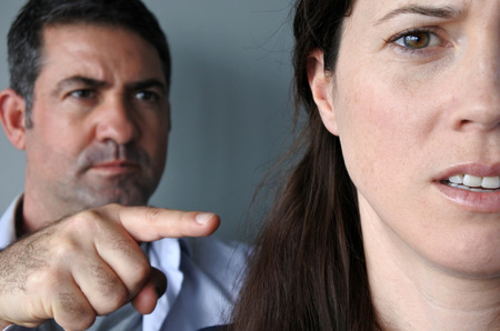 Portrait of a man blaming his wife. Unhappy young who have fallen out over a disagreement. Woman in the front and the man in the background. People relationship conceptの写真素材